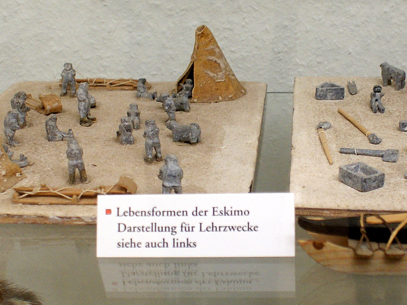 Eine Miniaturdarstellung zeigt traditionelle Lebensformen mit kleinen Figuren, Gebäuden und Booten in einer nordischen Landschaft.