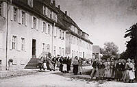 Eine große Gruppe von Menschen steht vor einem historischen Gebäude in schwarz-weiß.