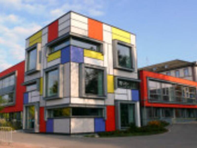 Ein modernes Gebäude mit einer Fassade in den Farben Rot, Blau, Gelb und Weiß, die in geometrischen Formen angeordnet sind.