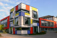 Ein modernes Gebäude mit einer Fassade in den Farben Rot, Blau, Gelb und Weiß, die in geometrischen Formen angeordnet sind.